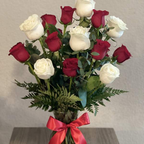 Bouquet of red and white roses in a glass vase with a red ribbon