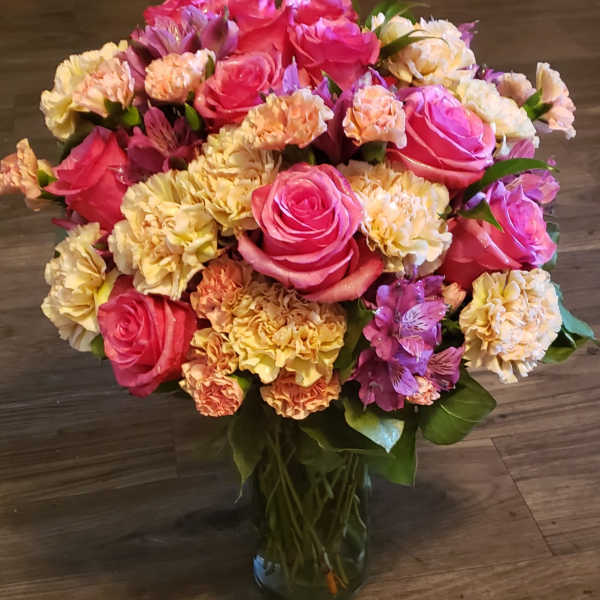 Bouquet of pink roses and peach carnations in a glass vase