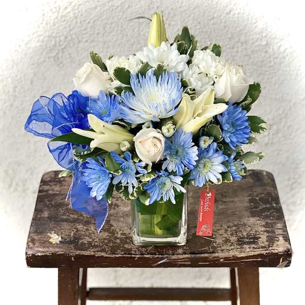 Blue and white mixed bouquet in a square glass vase with a ribbon