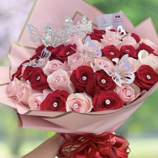 Bouquet of red and pink roses with butterfly picks and a tiara topper