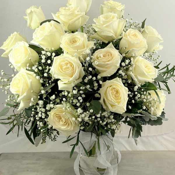 Bouquet of cream roses with baby's breath in a glass vase