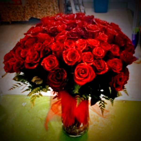 Bouquet of red roses in a glass vase with a red ribbon