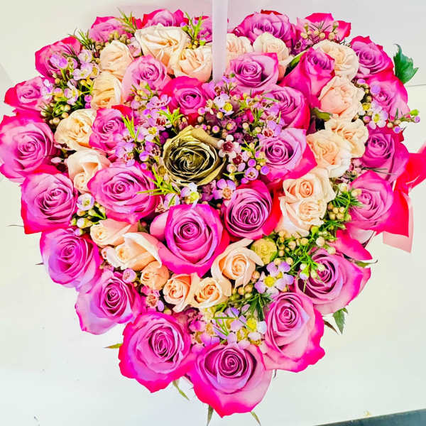 Heart-shaped bouquet of pink and peach roses with small filler flowers