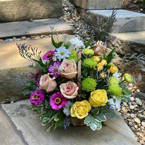 Mixed bouquet with roses, daisies, and bright mums in a basket