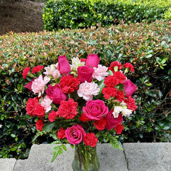 Pink roses and red carnations arranged in a glass vase