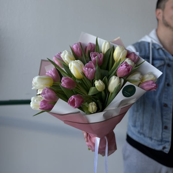 Bouquet of pink, white, and yellow tulips wrapped in pink paper