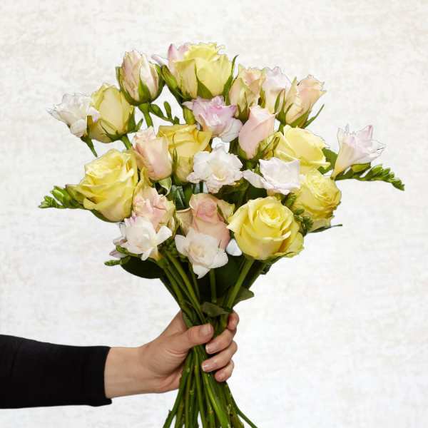 Handheld bouquet of pale yellow and blush roses