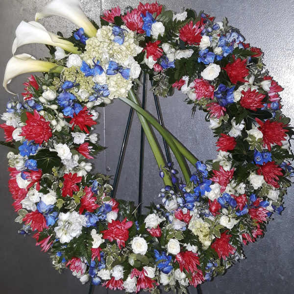 Circular floral wreath with white calla lilies and red, blue, and white blooms