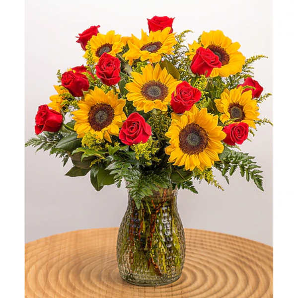 Sunflowers and red roses arranged in a glass vase
