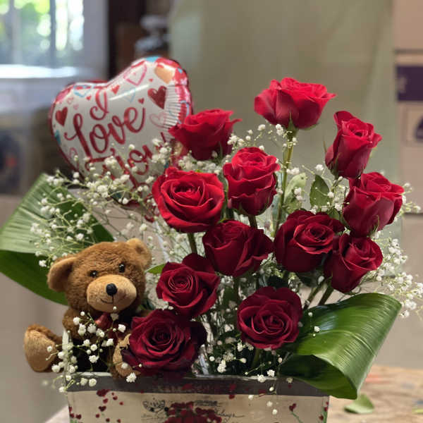 Red roses in a gift box with a teddy bear and heart balloon