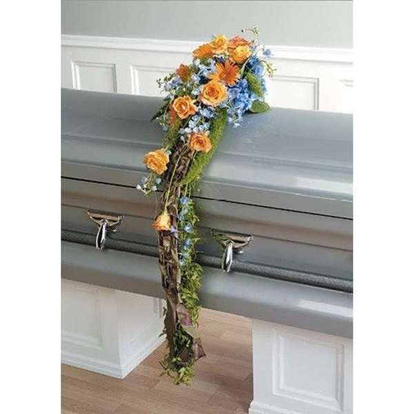 Floral casket spray with orange roses and blue flowers on a gray casket