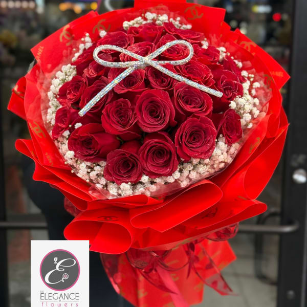 Bouquet of red roses wrapped in bright red paper with a silver bow