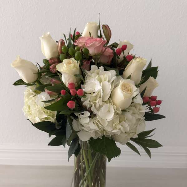 Bouquet of white and pink roses with hydrangeas in a clear glass vase