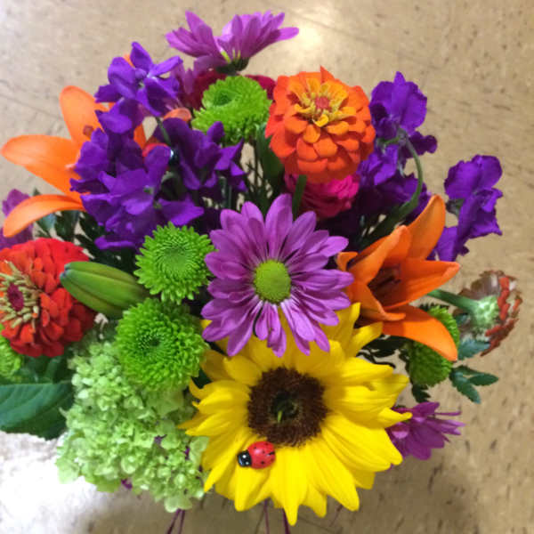Colorful mixed bouquet with sunflower, lilies, and purple daisies