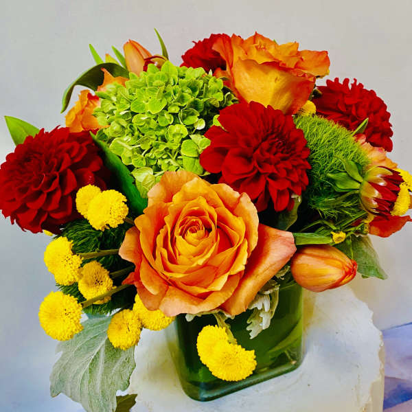 Bouquet of orange and red flowers in a green glass vase