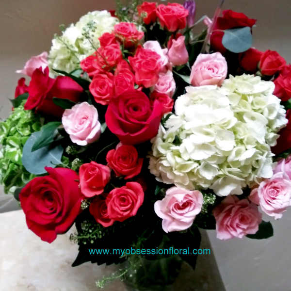 Bouquet of red, pink, and white roses with hydrangeas