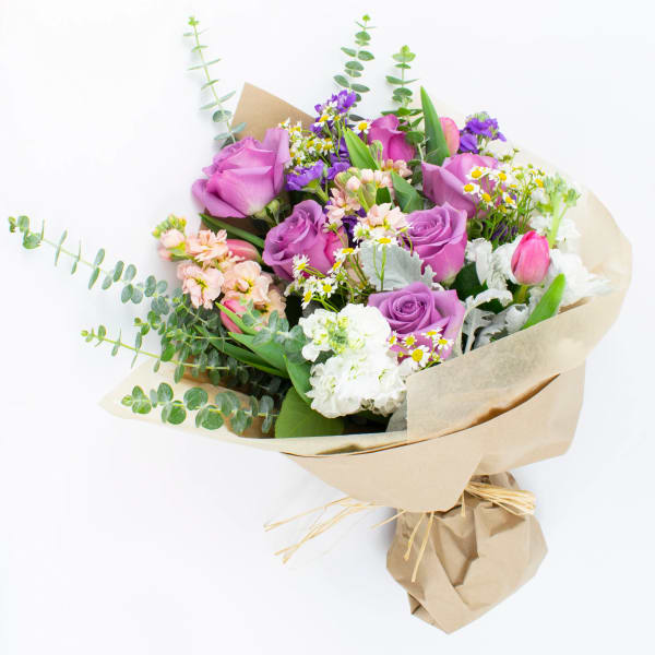 Bouquet of purple roses and mixed small flowers wrapped in kraft paper