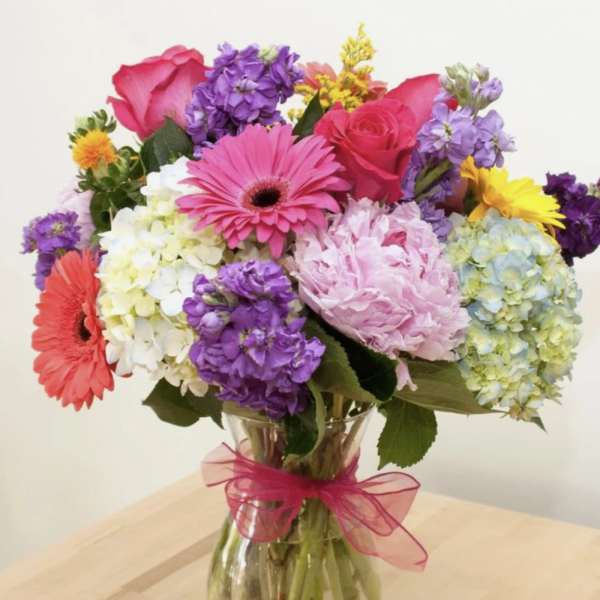 Mixed bouquet of pink, purple, yellow, and white flowers in a glass vase
