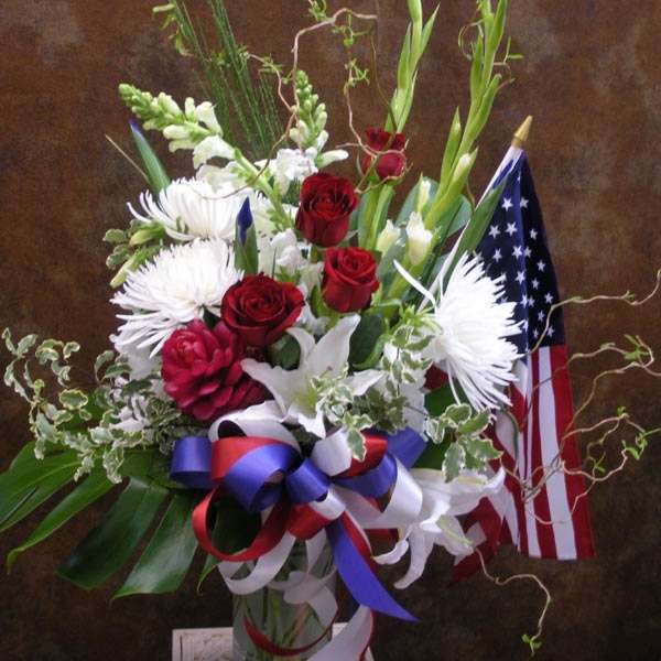 Red roses and white flowers in a vase with an American flag