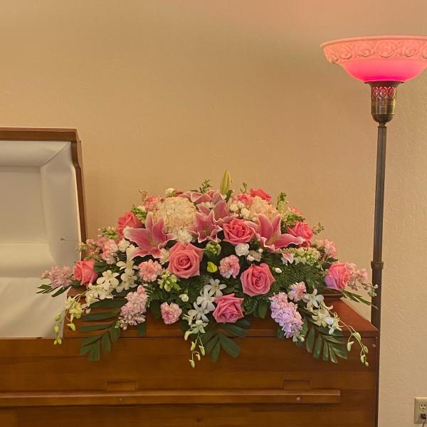 Pink and white floral arrangement on a wooden casket