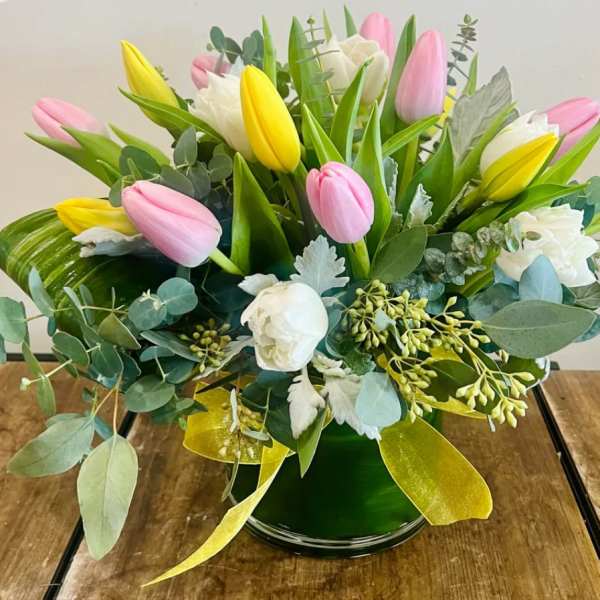 Pink, yellow, and white tulips arranged in a green vase