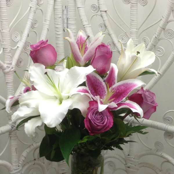 Pink and white lilies with roses in a clear glass vase