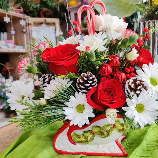Red roses and white daisies arranged in a decorative sleigh container