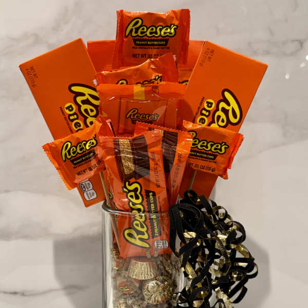 Reese's candy bouquet in a clear glass vase with black and gold ribbon curls