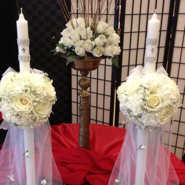 White floral wedding candles with rose arrangements and tulle