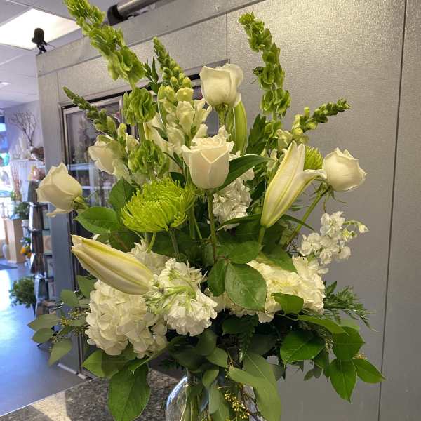 White roses and lilies arranged in a clear glass vase