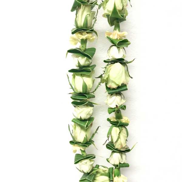 Two white rose leis with green accents on a white background