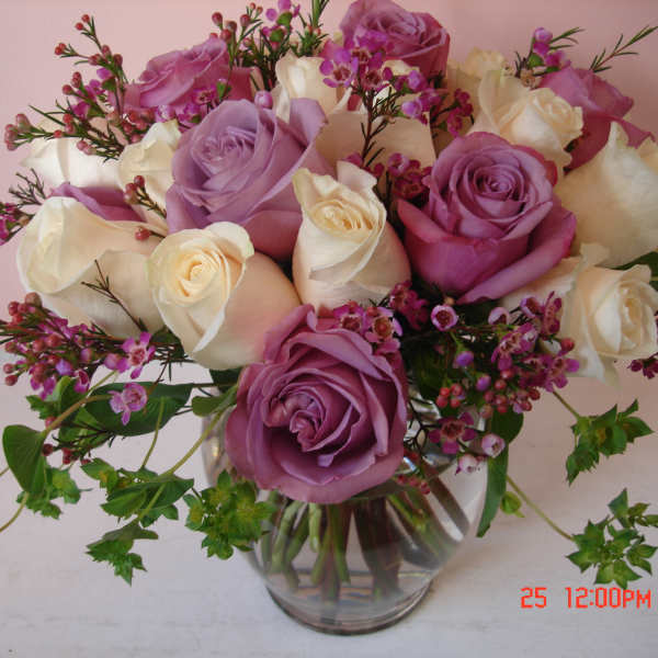 Bouquet of pink, lavender, and white roses in a clear glass vase