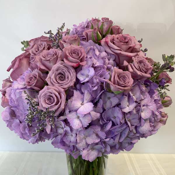 Lavender roses and hydrangeas in a clear glass vase