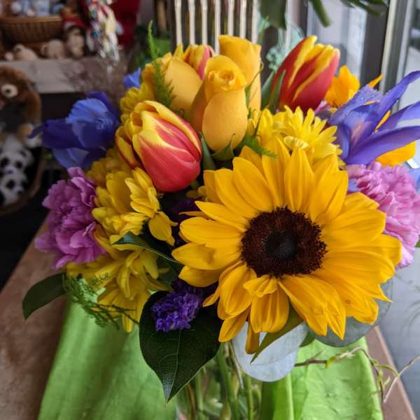 Bouquet of sunflowers, tulips, and purple flowers in a glass vase