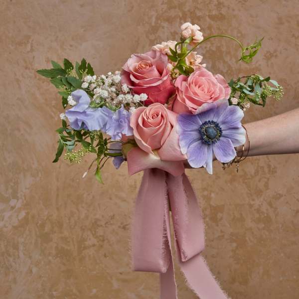 Hand-tied bouquet of pink roses and lavender flowers with a pink ribbon
