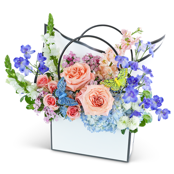 Pastel flower arrangement in a white handled box with butterfly accents