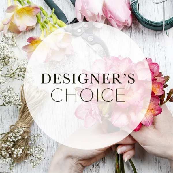 Hands holding a pink floral crown with flowers and twine on a white wood surface
