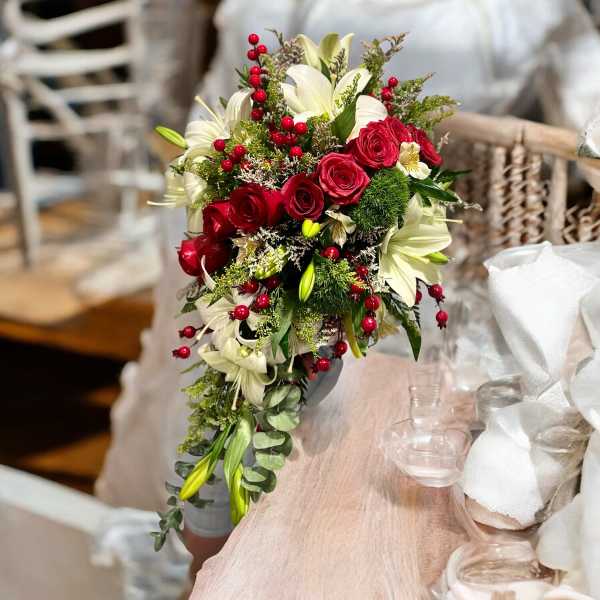 Bouquet of red roses and white lilies with berry accents