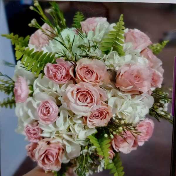 Pink roses and white flowers arranged in a hand-held bouquet