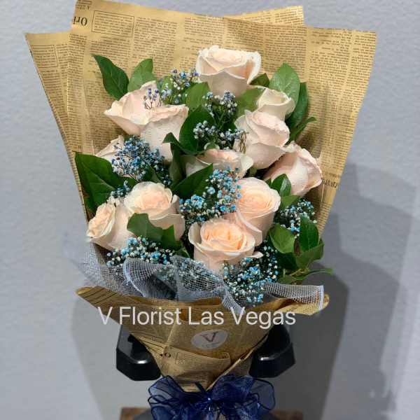 Bouquet of pale peach roses with blue filler flowers in newspaper-style wrap