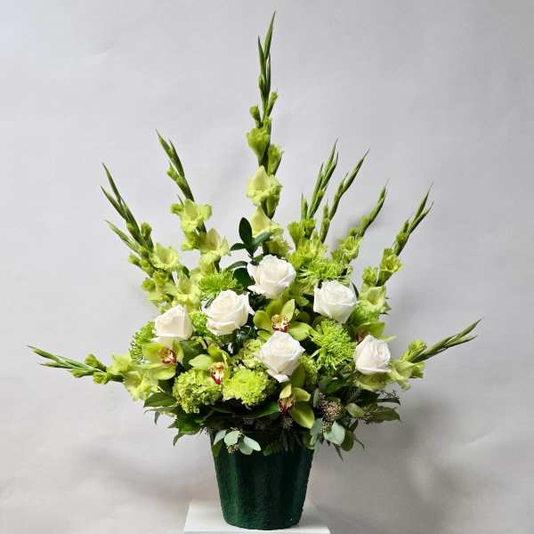 White roses and green flowers in a dark vase