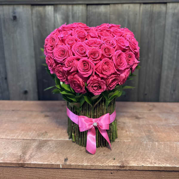 Heart-shaped bouquet of hot pink roses tied with a pink ribbon
