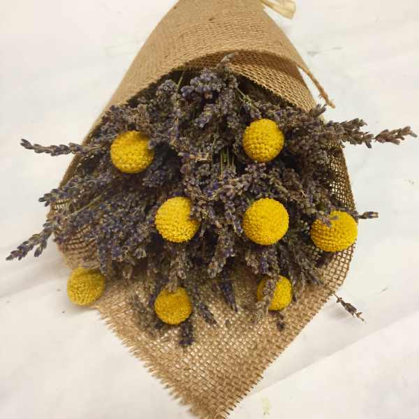 Bundle of dried purple flowers with yellow pom-pom blooms wrapped in burlap