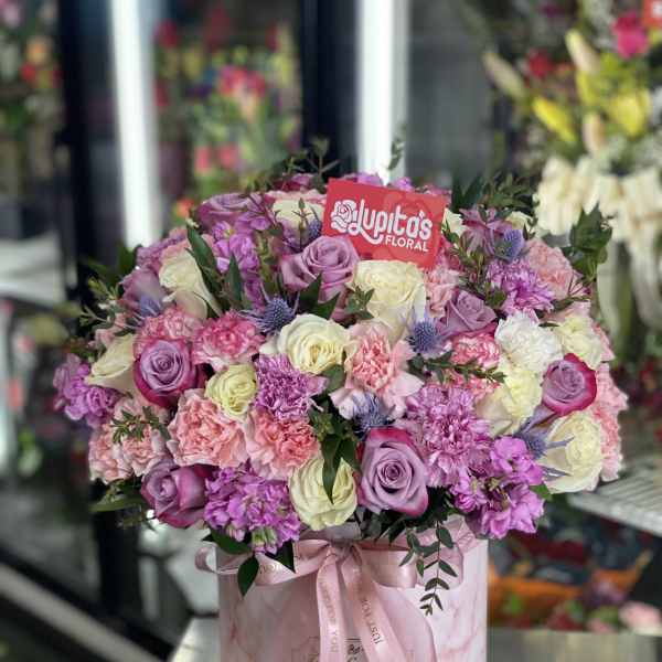 Pink and lavender rose bouquet in a round gift box with a ribbon