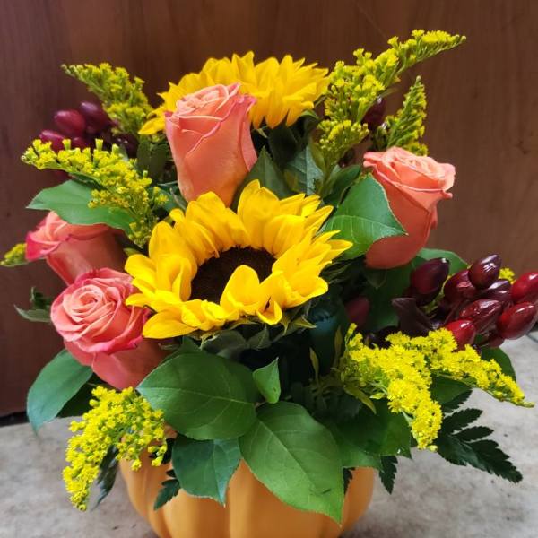 Pumpkin-shaped vase with sunflowers and peach roses