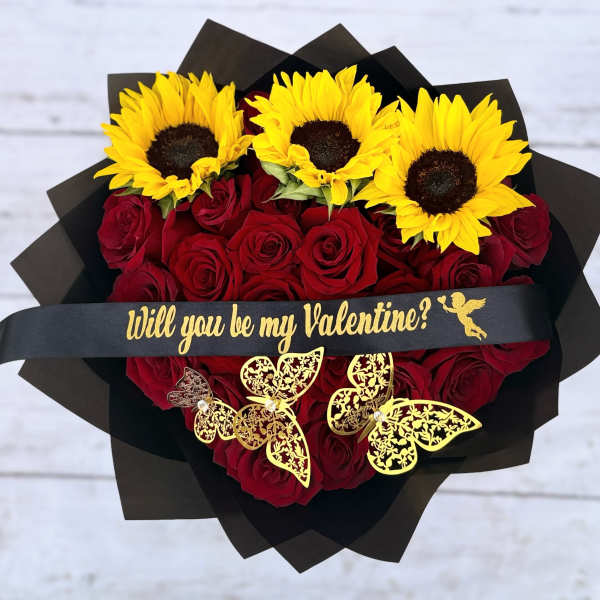 Heart-shaped bouquet of red roses topped with yellow sunflowers