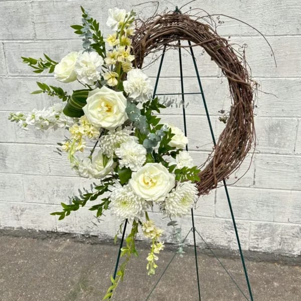 White floral arrangement on a grapevine crescent wreath stand