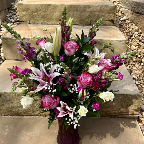 Pink and white mixed flower arrangement in a purple vase