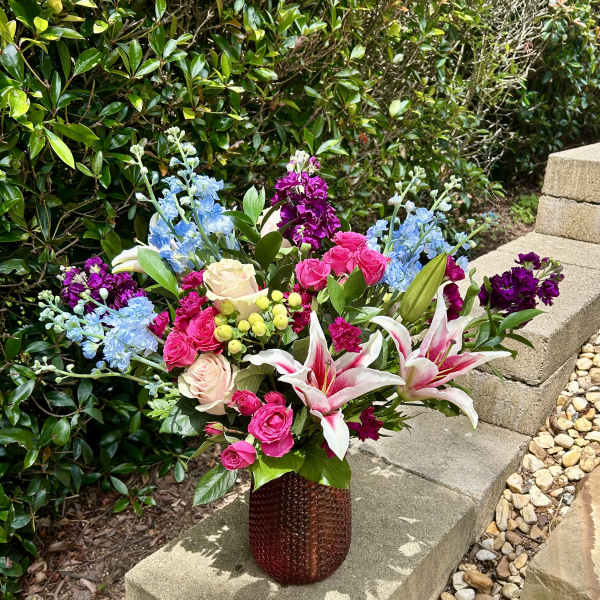 Mixed bouquet in a textured vase with pink roses and lilies