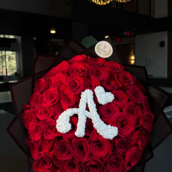 Large bouquet of red roses with a white floral monogram